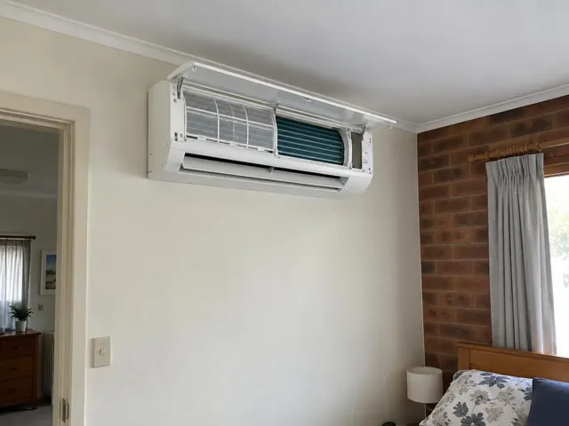 Clean split system on an interior wall with open front panel and visible filters in a bedroom in Hillbank