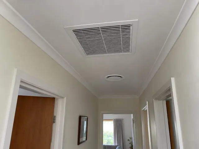 Hallway ceiling with a return-air grille and round ceiling outlet in a cream interior in Elizabeth East